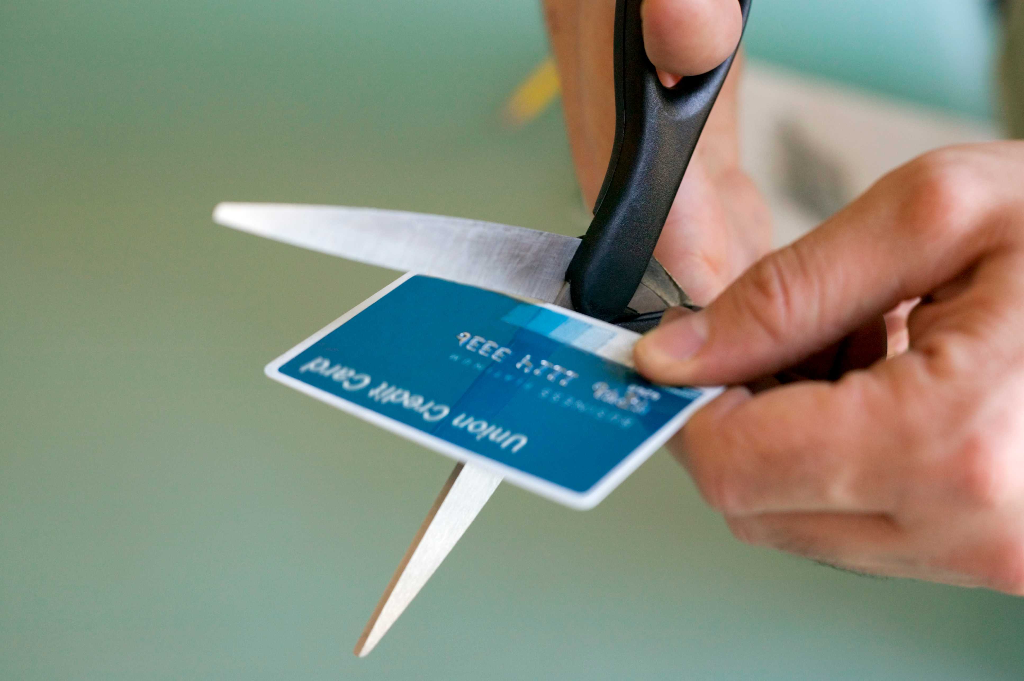 Consumidor cortando cartão: risco de dívida de cartão de crédito e superendividamento