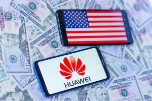 Dois aparelhos celulares, um ao lado do outro, mostrando em suas telas a bandeiras dos Estados Unidos e o logo da Huawei.