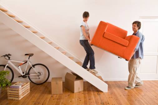 Couple carrying armchair up stairs