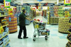 Homem com carrinho de supermercado entre as prateleiras de alimentos
