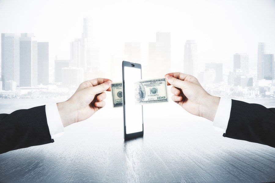 Dinheiro sendo transferido por meio de um celular para simbolizar a transa&ccedil;&atilde;o digital