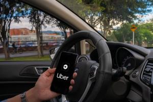 Homem segurando celular com o aplicativo do Uber