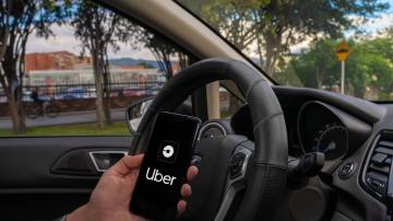 Homem segurando celular com o aplicativo do Uber