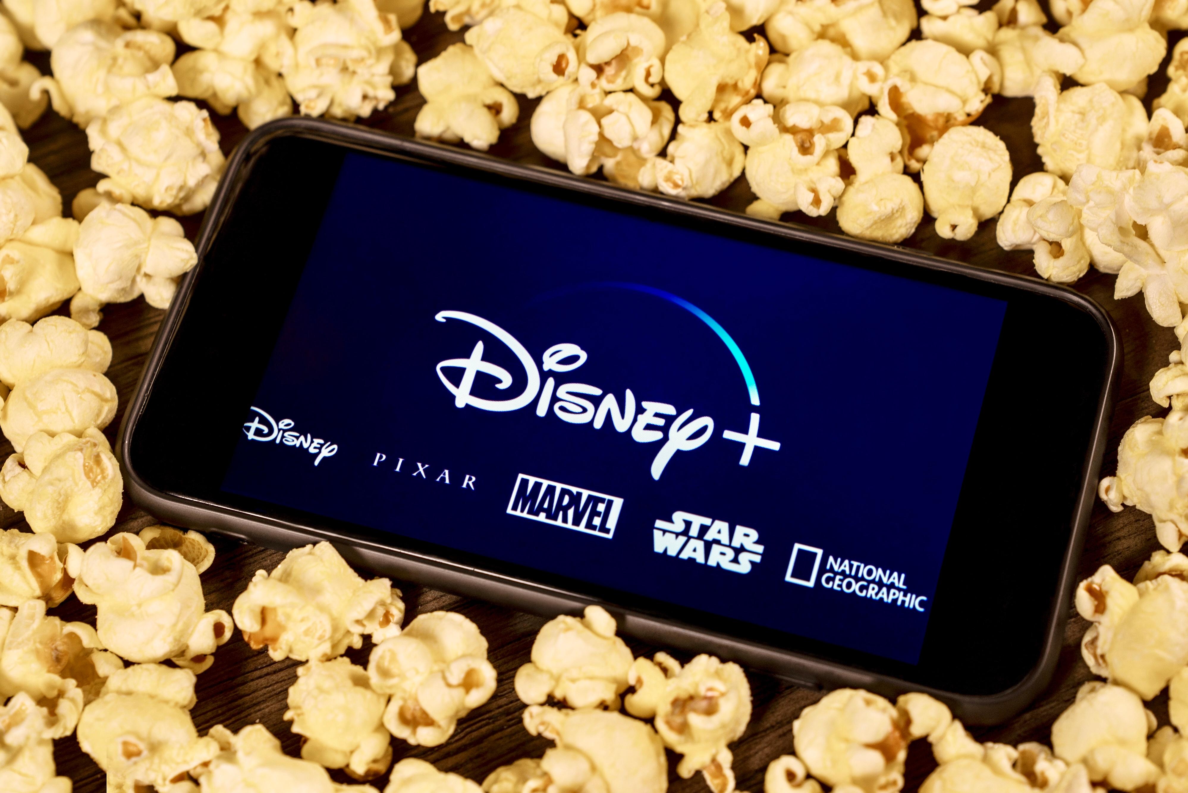 Celular com o aplicativo do Disney+ envolto de pipocas