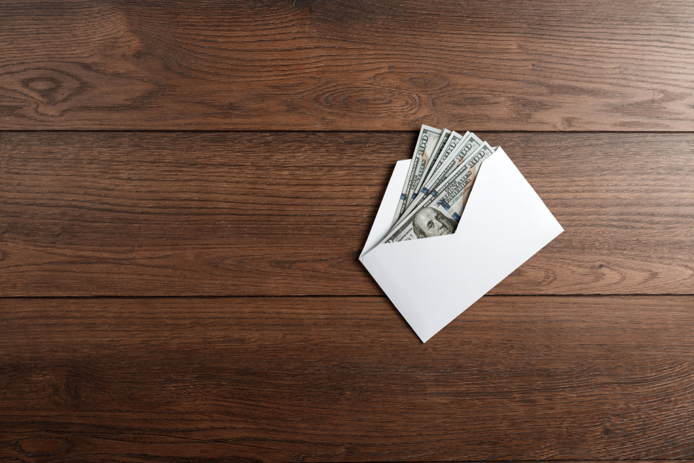 Envelope com notas de dólar sobre uma mesa de madeira