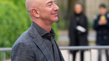 Jeff Bezos, CEO da Amazon, vestindo terno cinza, olhando para o lado direito