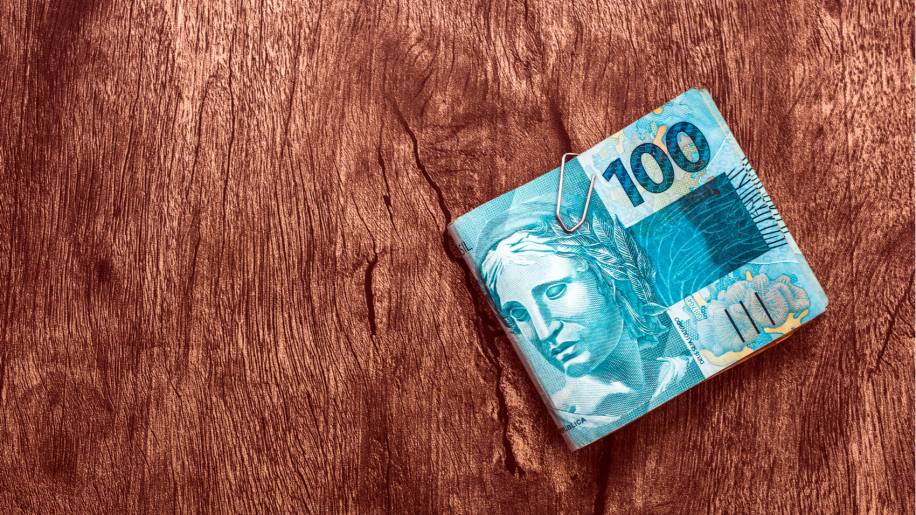 notas de R$ 100 em uma mesa de madeira reais dinheiro