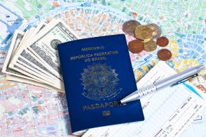 Passaporte brasileiro sob um mapa, rodeado de notas de dólares e moedas