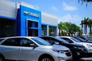 Concessionária da Chevrolet com a fachada azul e vários carros estacionados na frente da loja