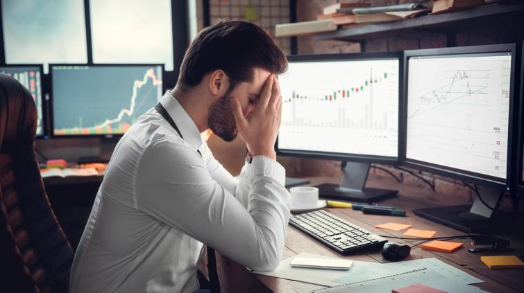Investidor triste, frustrado e com dor de cabeça por causa da queda em suas ações, investimentos