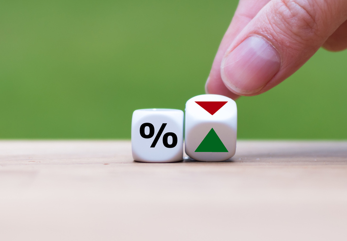 The hand rolls the dice and changes the direction of the arrow to indicate low interest rates (or vice versa).