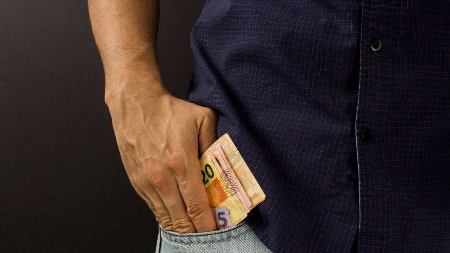 Homem com notas de dinheiro em reais no bolso