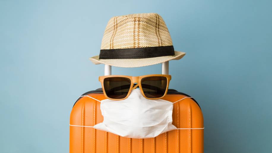 Turismo na pandemia, mala de viagem com máscara