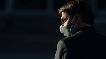 Foto de Bolsonaro usando uma máscara cirúrgica no rosto enquanto caminha em Brasília