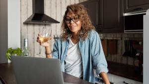 Mulher bebendo vinho e usando o computador (Matilda Wormwood/Pexels)