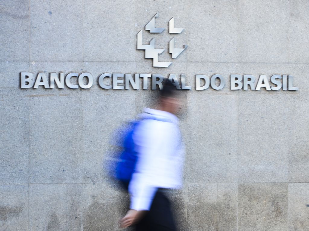 Foto em que um homem passa na frente do prédio do Banco Central do Brasil