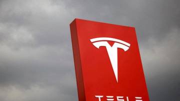 Fachada com logotipo da Tesla com céu nublado ao fundo