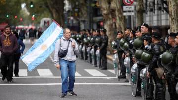 Manifestante segura uma bandeira argentina ao lado dos membros da polícia durante marcha do Primeiro de Maio, em Buenos Aires, na Argentina (Reuters/Agustin Marcarian)