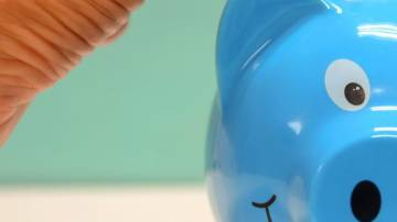 Cofrinho de porco azul recebendo moedas
