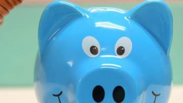 Cofrinho de porco azul recebendo moedas