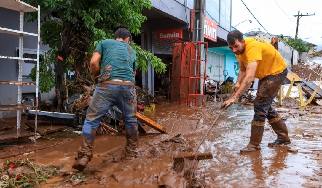 Moradores tentam limpar a sujeira e retirar a lama em região afetada pelas enchentes no Rio Grande do Sul (Foto: Gustavo Mansur/Palácio Piratini)