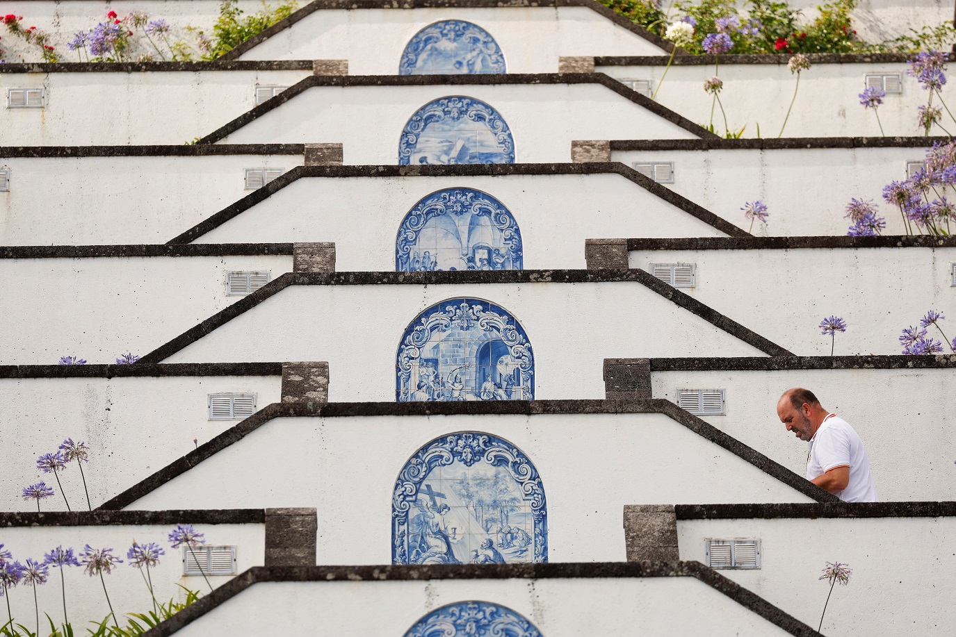 Um homem sobe a escadaria que leva à pequena capela "Ermida de Nossa Senhora da Paz" no topo de uma montanha com vista para Vila Franca Do Campo na Ilha de São Miguel, no arquipélago dos Açores, Portugal, em 2 de julho de 2024. REUTERS/Darrin Zammit Lupi