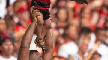 RIO DE JANEIRO, BRAZIL - DECEMBER 1: A supporter of Flamengo lifts a child during the match between Flamengo and Internacional at Maracana Stadium on December 1, 2024 in Rio de Janeiro, Brazil. (Photo by Max Peixoto/Eurasia Sport Images/Getty Images)