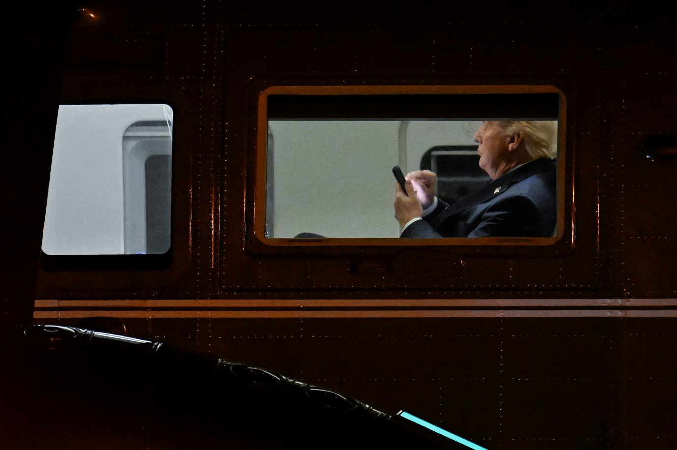 O presidente dos EUA, Donald Trump, usa seu telefone no Marine One no Aeroporto Executivo de Leesburg.