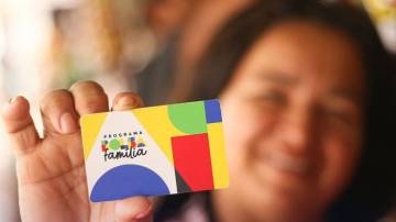 Mulher com cartão do Bolsa Família