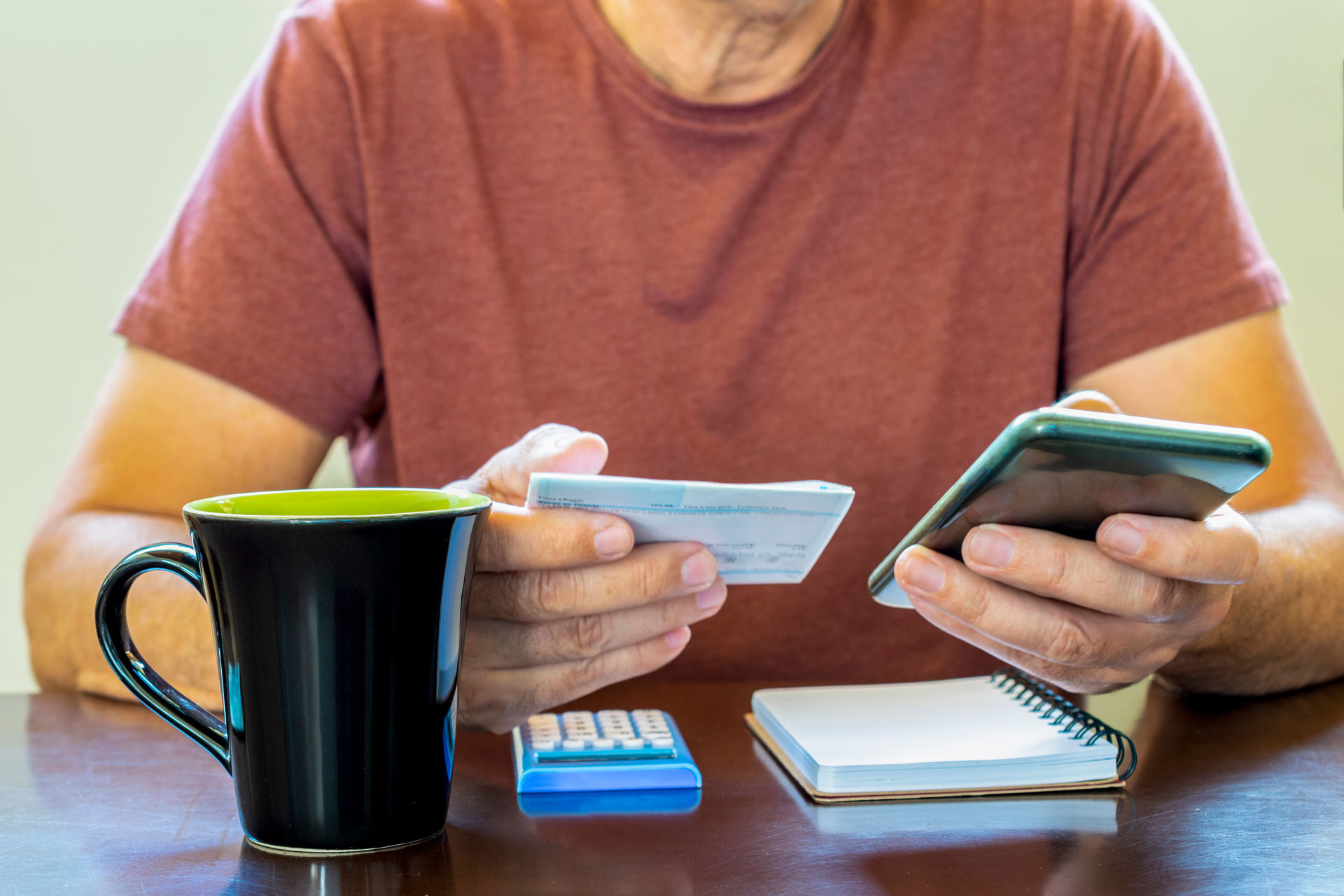 Pessoa coloca as contas em dia e calcula quanto gasta em suas contas de consumo como conta de luz, conta de telefone, conta de energia e conta de água