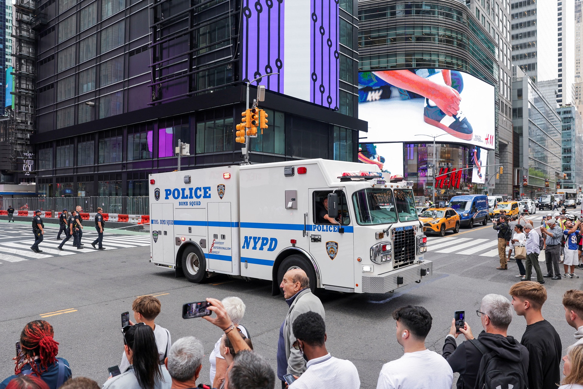 Pessoas usam seus celulares enquanto veículos policiais bloqueiam uma rua em uma área isolada na Times Square, em Nova York, EUA, em 18 de agosto de 2025. REUTERS/Jeenah Moon