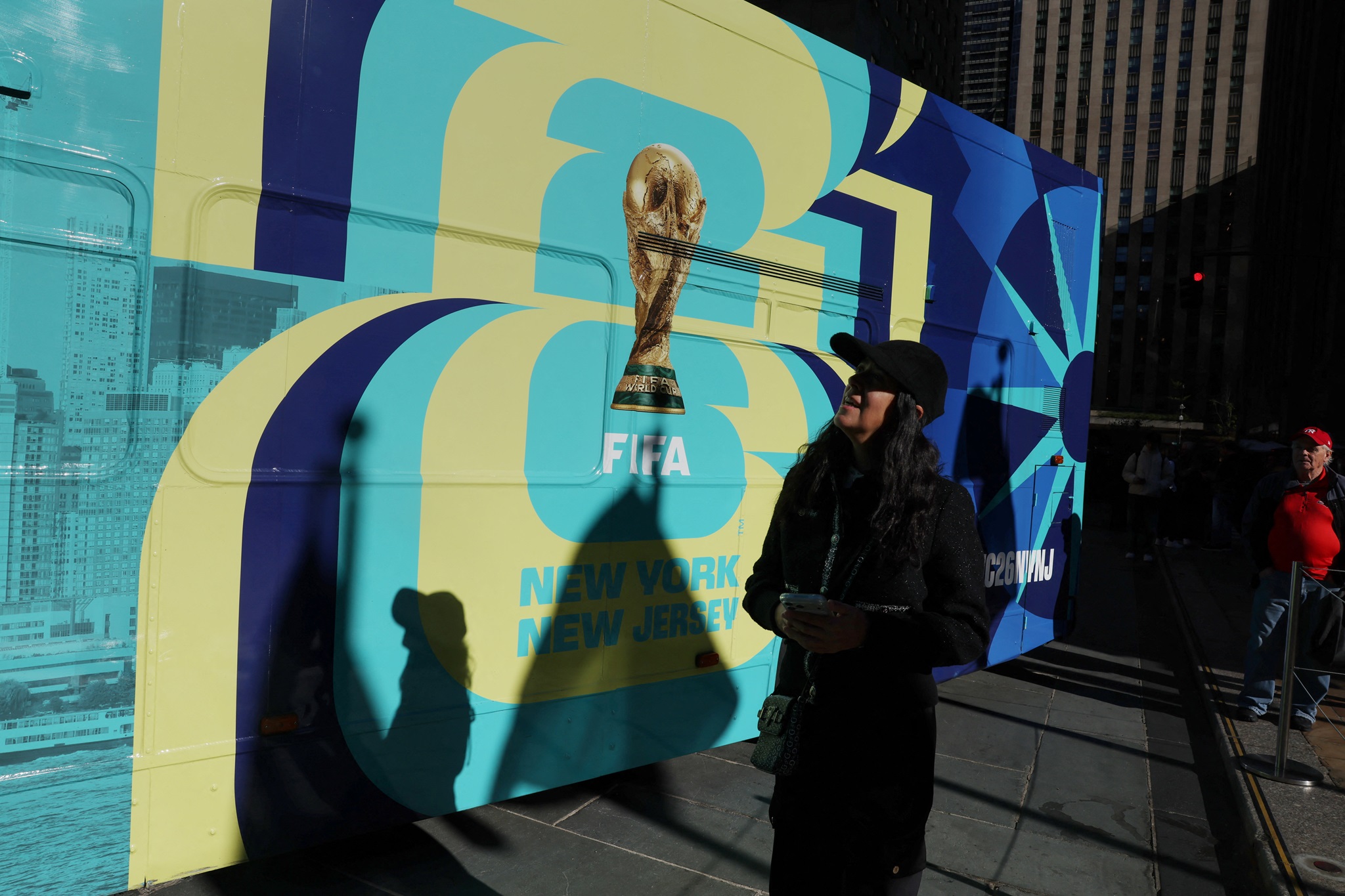 Uma mulher passa por um anúncio de ônibus da Copa do Mundo FIFA 26 Nova York e Nova Jersey no Rockefeller Center, em Nova York, EUA, 23 de outubro de 2025. REUTERS/Shannon Stapleton