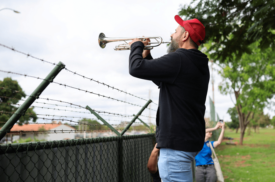 Fabiano Leitão toca trompete enquanto protesta contra o ex-presidente do Brasil, Jair Bolsonaro, em frente à Superintendência Regional da Polícia Federal, onde Jair Bolsonaro foi levado após ser colocado sob custódia da polícia federal como medida preventiva relacionada à sua prisão domiciliar, em Brasília, Brasil, 22 de novembro de 2025. REUTERS/Mateus Bonomi