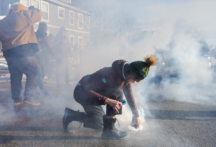 Manifestantes cobre lata de gás lacrimogêneo durante protesto contra agentes de imigração em Minneápolis, nos Estados Unidos