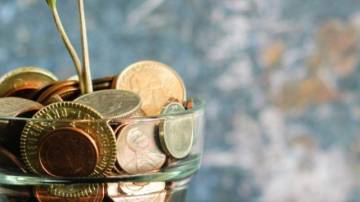 copo de vidro com moedas sobre a mesa