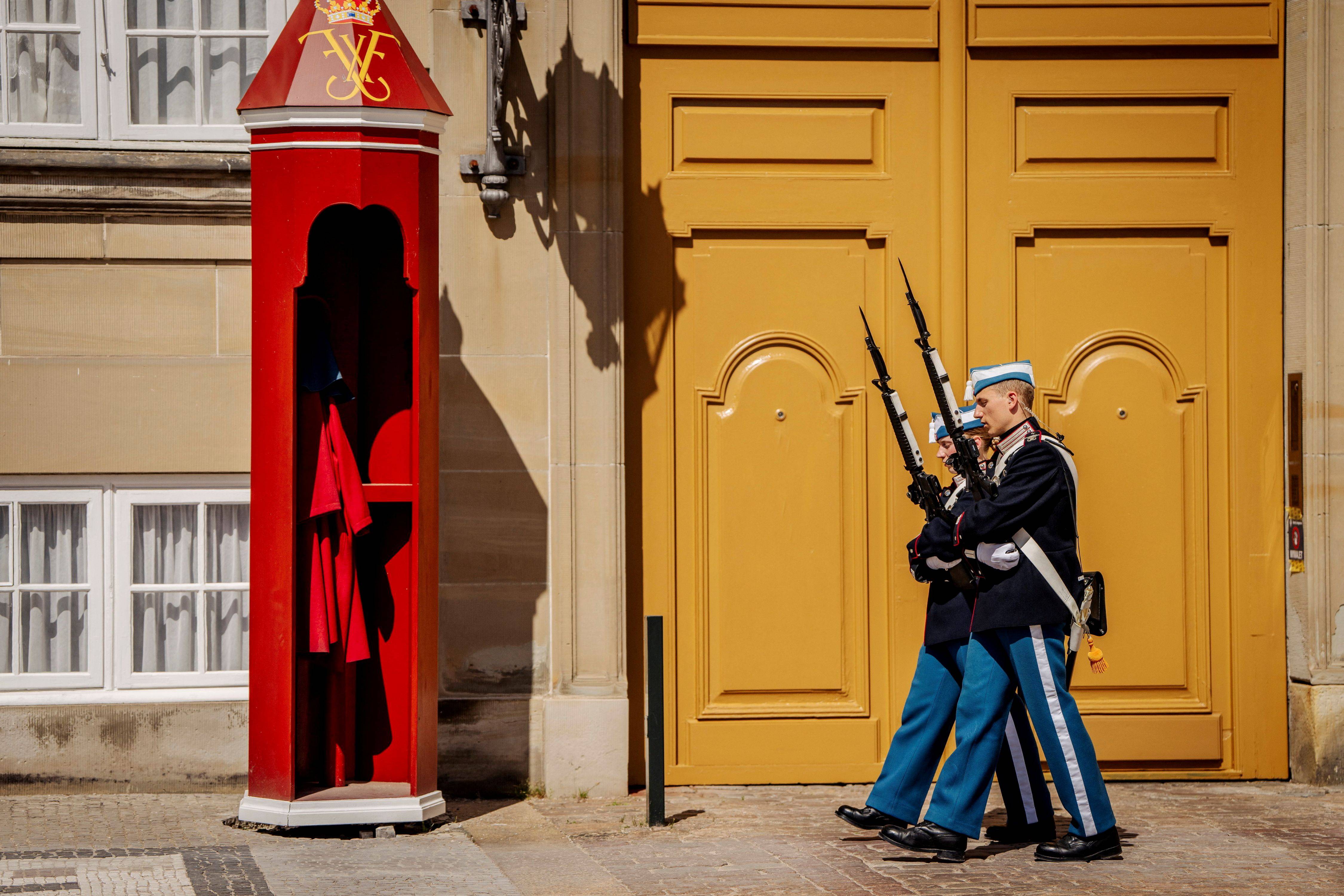 Guardas sem seus chapéus de pele de urso caminham durante a onda de calor no Palácio de Amalienborg, no centro de Copenhague, Dinamarca, na sexta-feira, 26 de junho de 2026. Ritzau Scanpix/Mads Claus Rasmussen via REUTERS