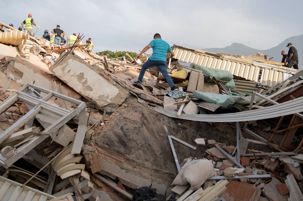 Um voluntário caminha sobre os escombros de um prédio desabado após os dois terremotos em Caraballeda, no estado de La Guaira, na Venezuela, em 25 de junho. Fotógrafo: Donaldo Barros/AFP/Getty Images/via Bloomberg