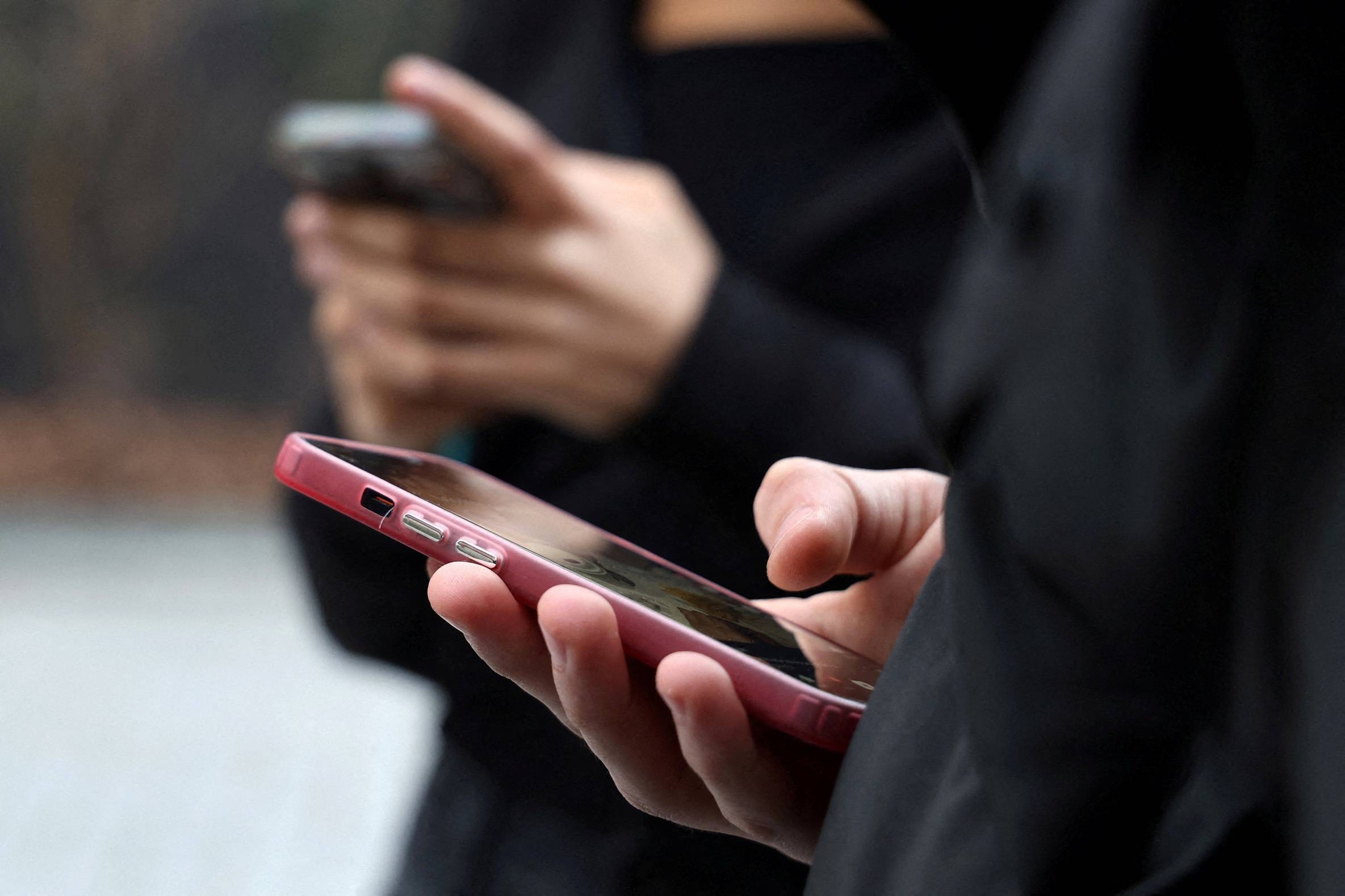 Adolescentes olham para as telas de seus celulares durante entrevista à Reuters sobre o projeto de lei que visa proibir o uso de redes sociais para menores de 15 anos e o uso de celulares nas escolas a partir do início do ano letivo de 2026, em Paris, França, 20 de fevereiro de 2026. REUTERS/Manuel Ausloos/Foto de arquivo