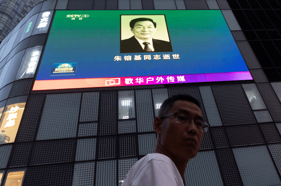 Um homem observa uma tela gigante em um shopping center que exibe a imagem do ex-primeiro-ministro chinês Zhu Rongji, falecido na quarta-feira, em Pequim, China