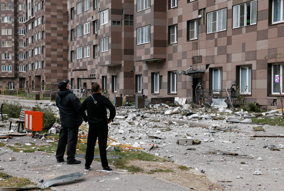 Homens no pátio de um prédio residencial de vários andares danificado — atingido pelo que as autoridades descreveram como um ataque de drone ucraniano, em meio ao conflito entre Rússia e Ucrânia — em Kotelniki, na região de Moscou, Rússia, em 20 de setembro de 2026.